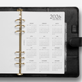 Black planner with a white calendar page for 2026 on a white background