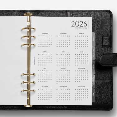 Black planner with a white calendar page for 2026 on a white background